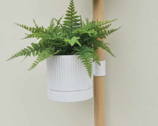 Vertical plant stand with three potted plants against a plain wall.