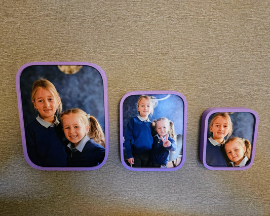 Three square photo frames with children's portraits on a textured surface