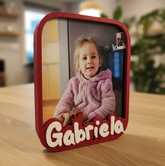 Red photo frame with a picture of a child and the name 'Gabriela' on a wooden surface.