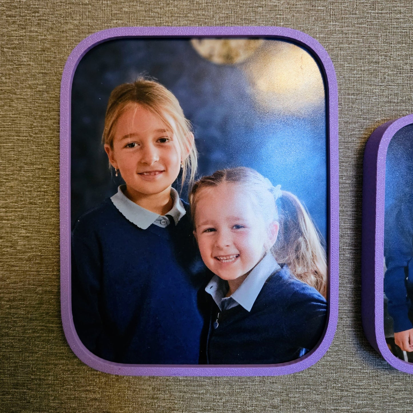 Two children in school uniforms with a purple border on a textured surface