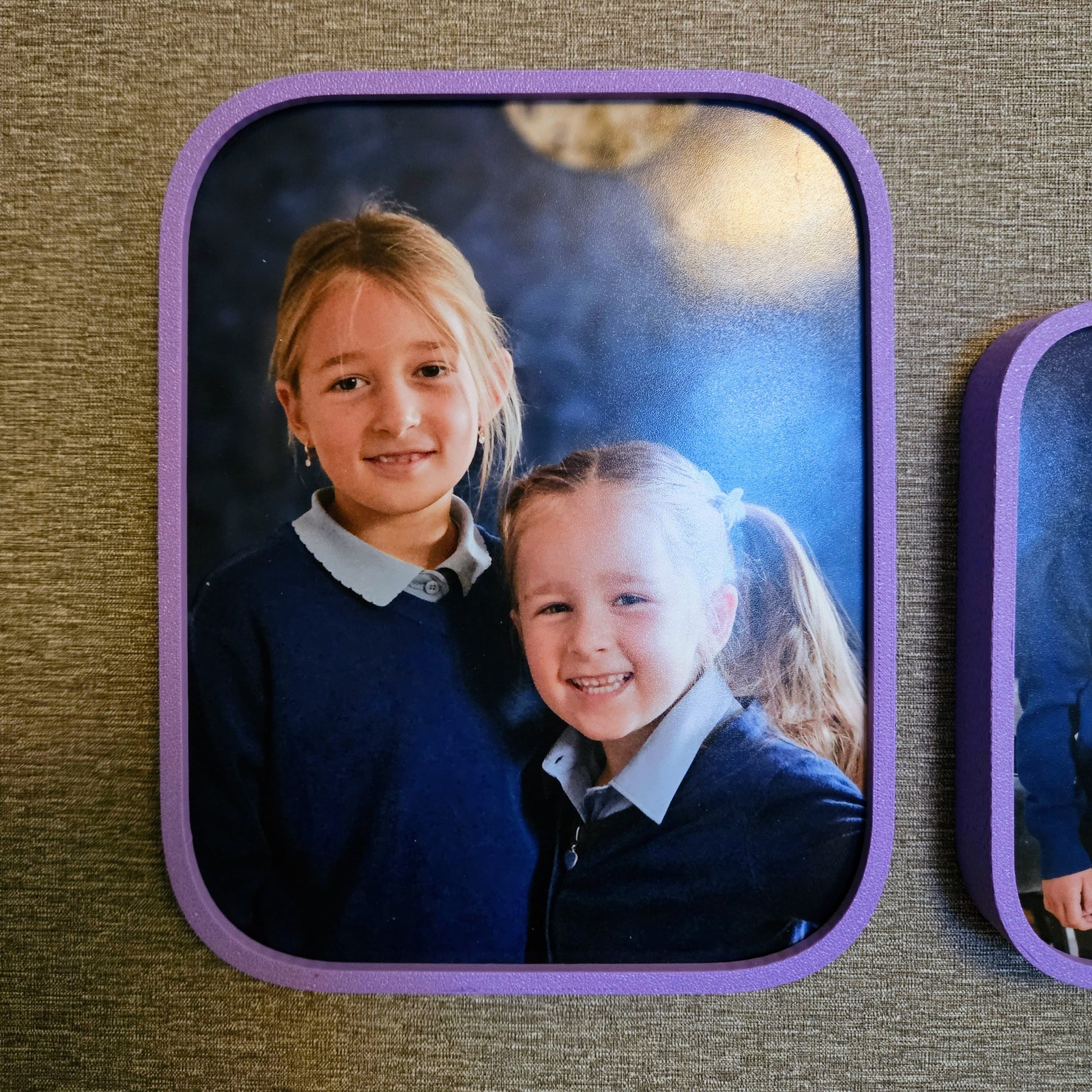 Two children in school uniforms with a purple border on a textured surface