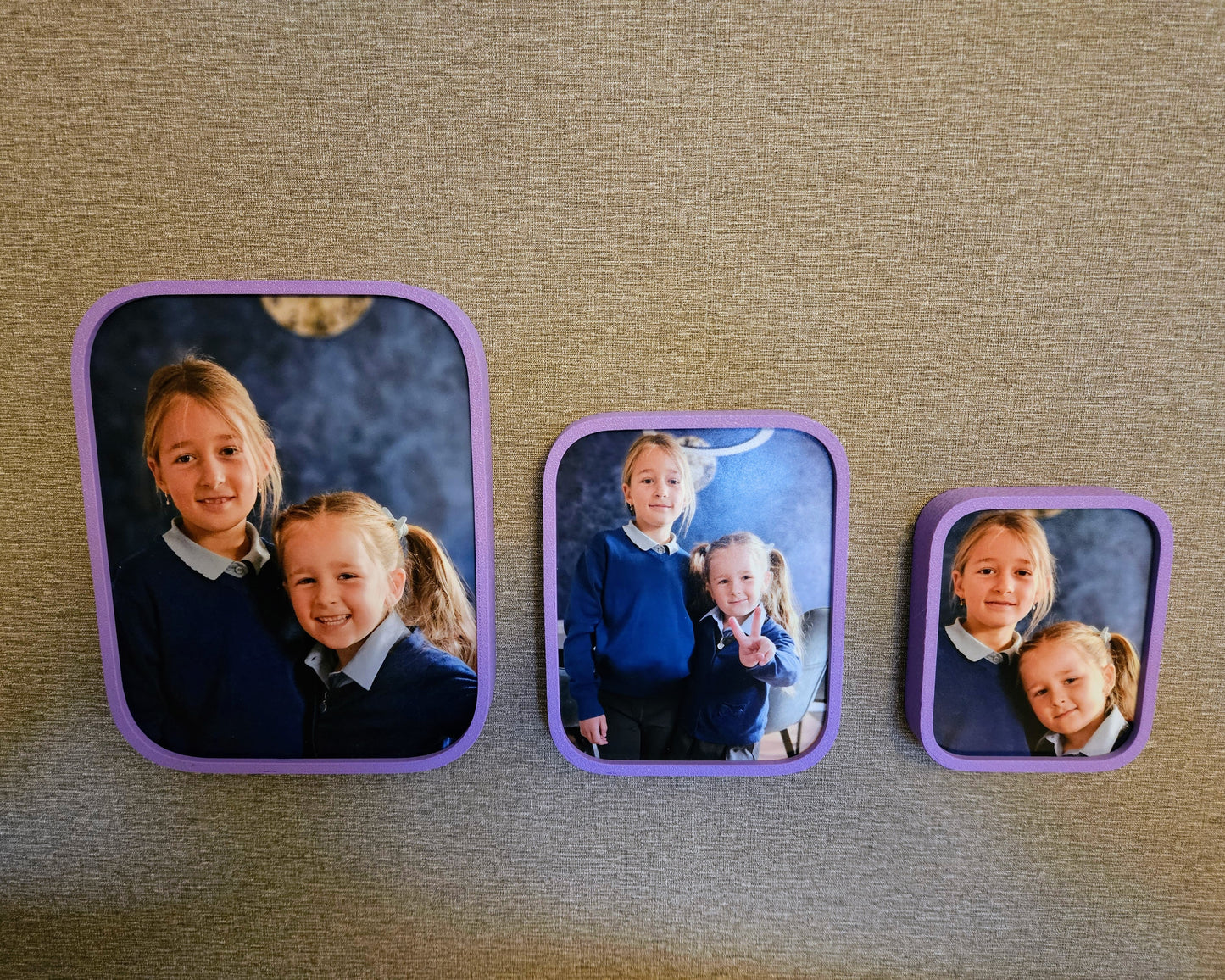 Three square photo frames with children's portraits on a textured surface