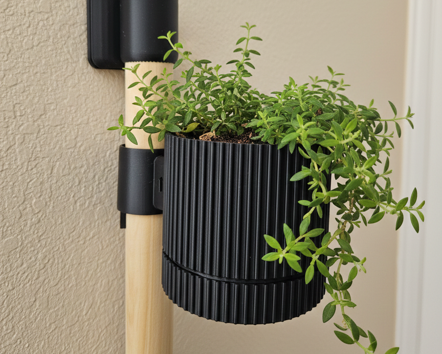 Black wall-mounted plant holder with a green plant against a beige wall.
