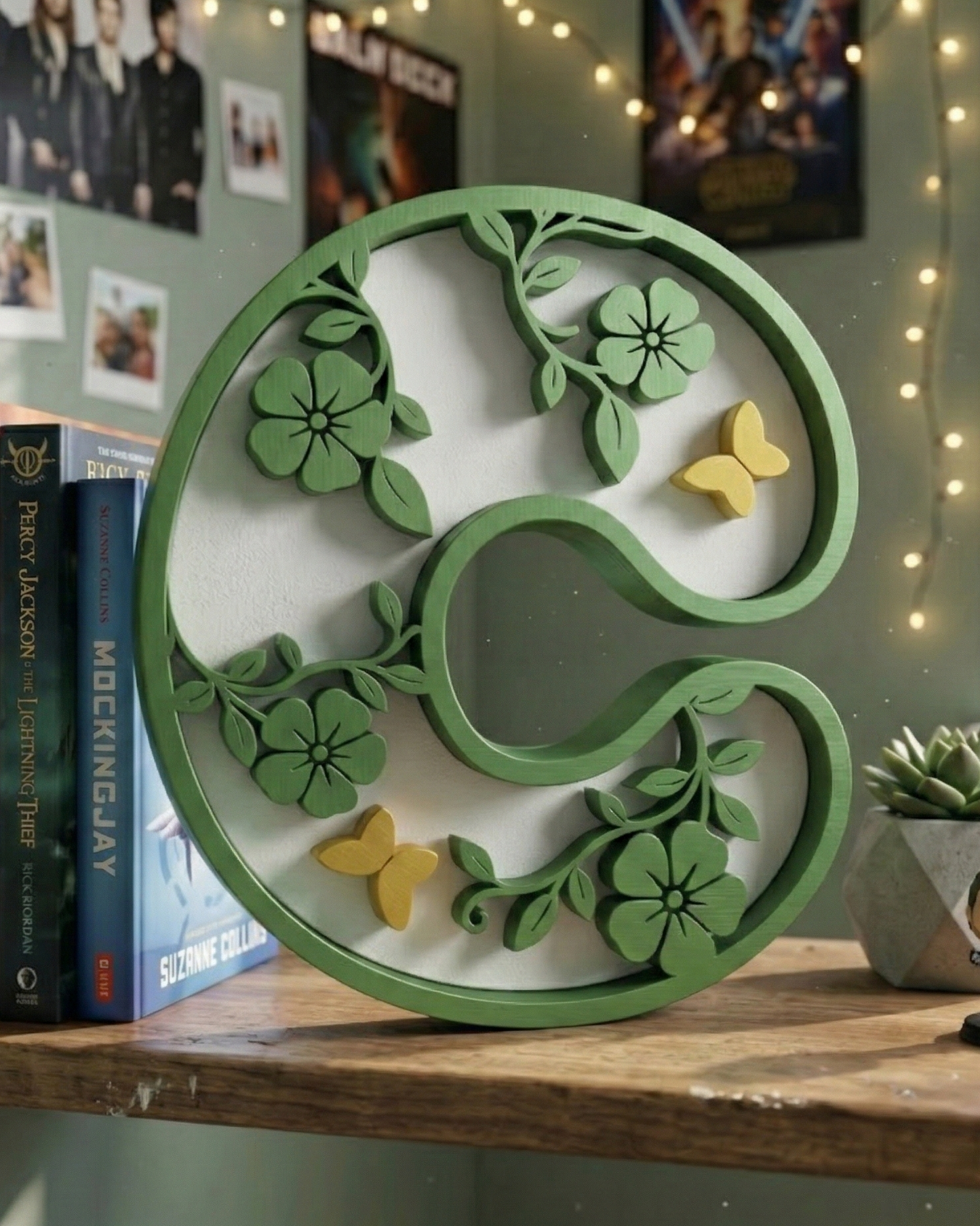 Decorative green letter 'C' with floral and butterfly designs on a shelf.