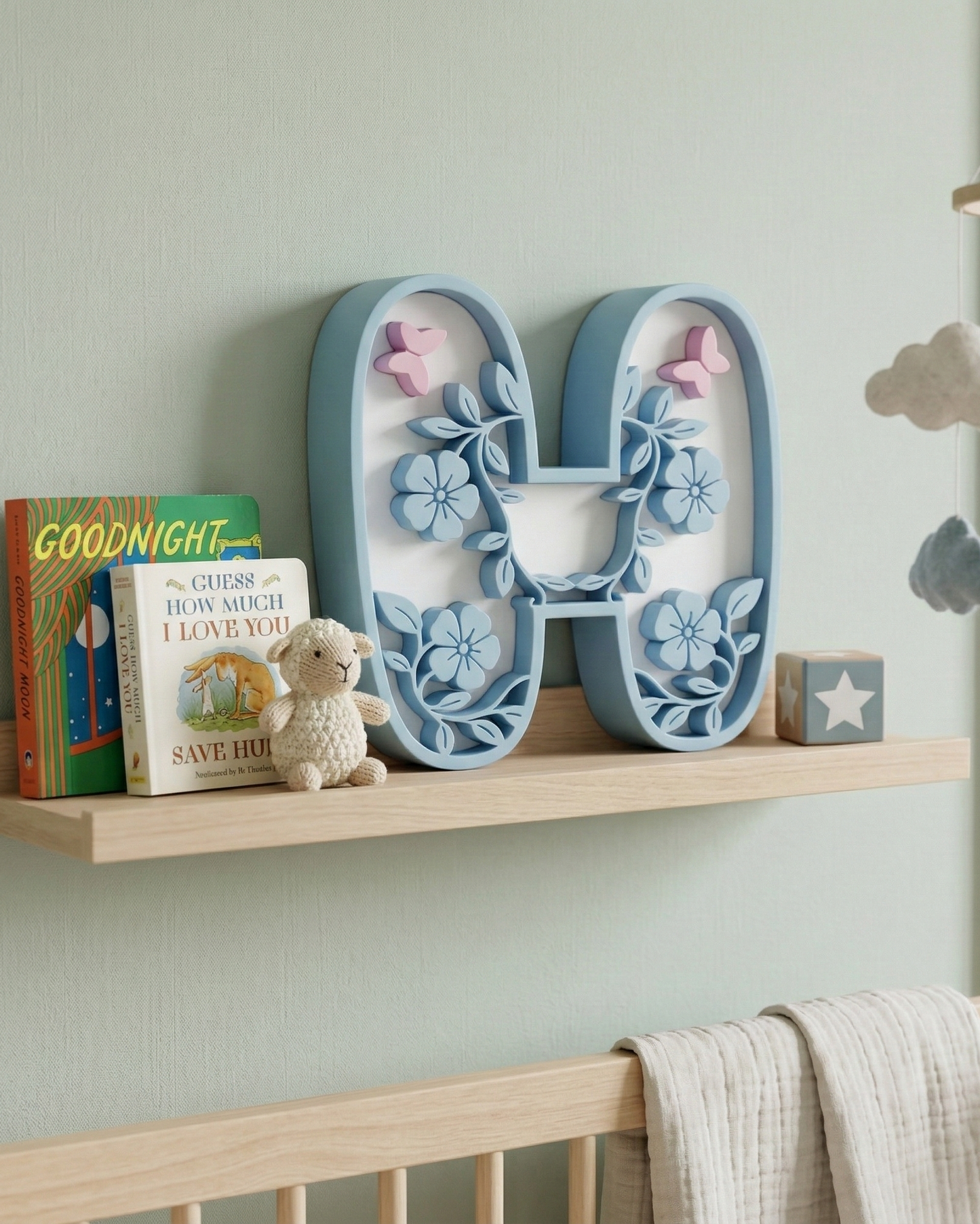 Decorative letter 'H' with floral designs on a shelf in a nursery.