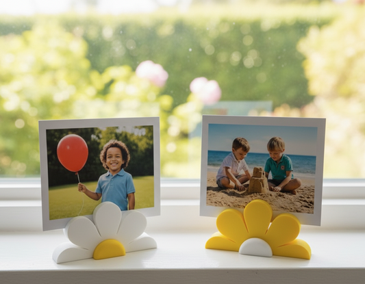Two photo frames on a windowsill with children's pictures, one with a red balloon and the other by the beach.